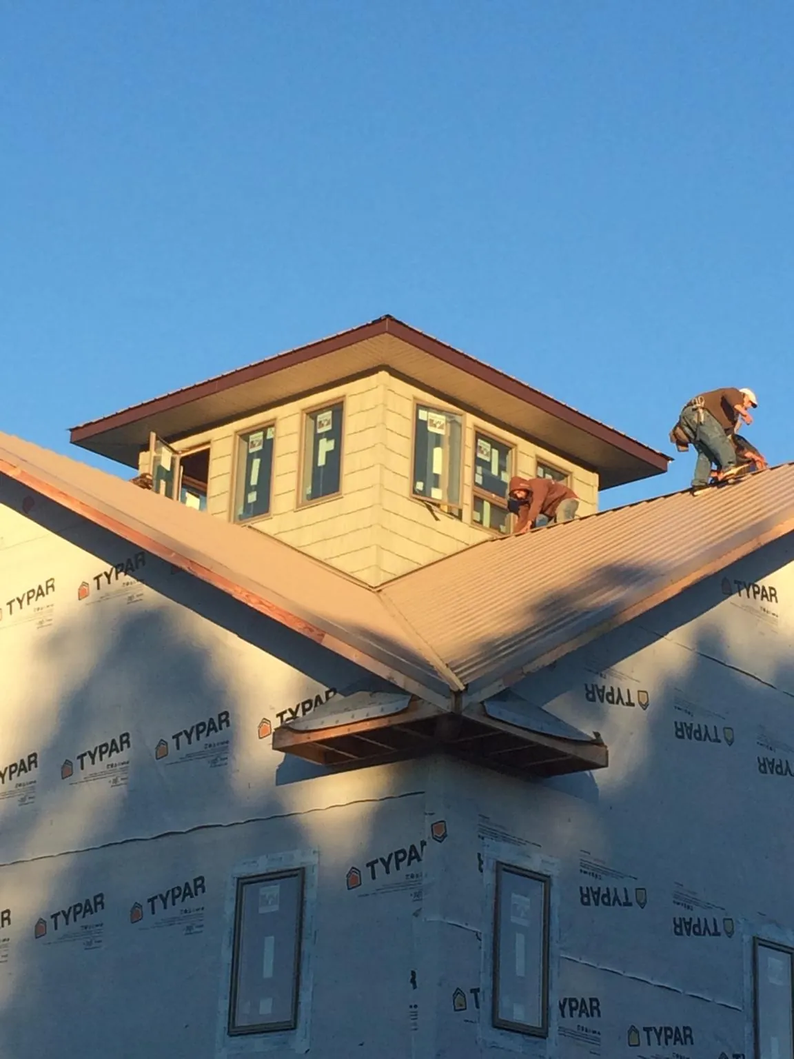 Roofers working around a rooftop cupola on a new metal roof at sunset — Roof Waterproofing in Davenport by Roofing Brothers